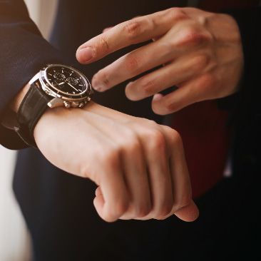 A woman checking the time on her luxury wrist watch bought using carefully invested funds.